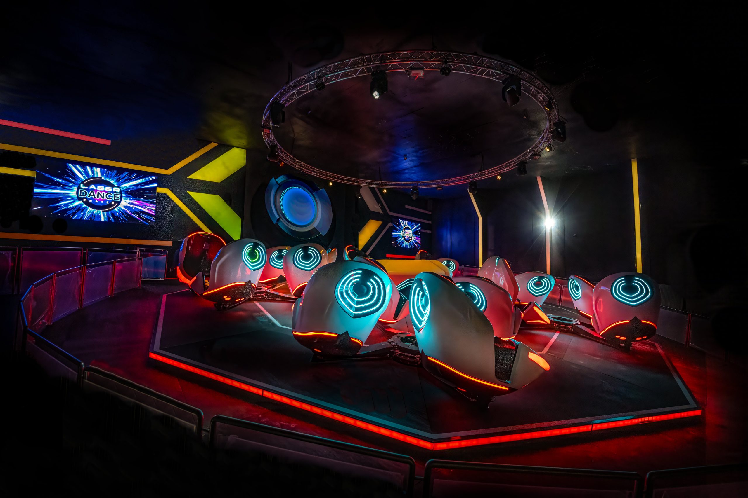 Futuristischer Innenraum der Breakdance 5 Attraktion im Laserdance Prater, mit Neonlichtern beleuchteten Sitzen.