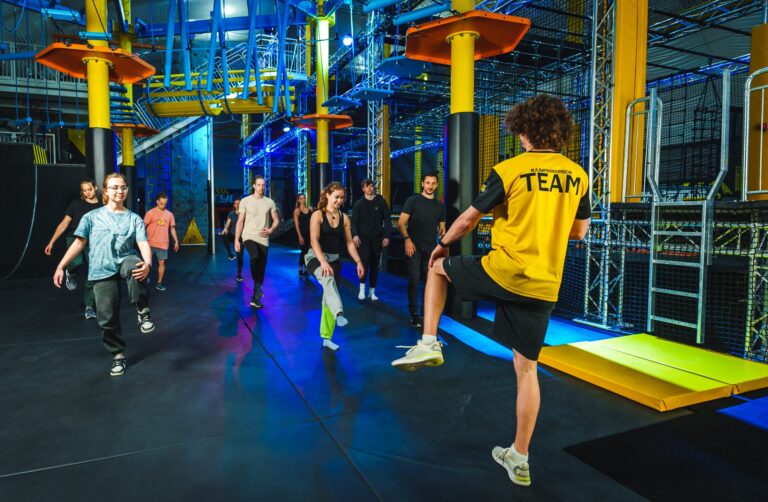 Gruppe junger Menschen beim Aufwärmen vor einem Indoor-Action-Parcours bei laserdance.at im Prater Wien