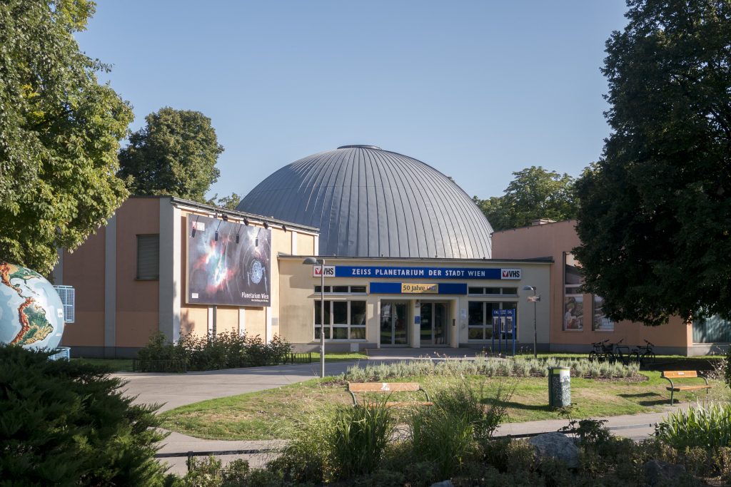 Planetarium der Stadt Wien mit großer Kuppel, Eingangsbereich und Grünanlage unter blauem Himmel.
