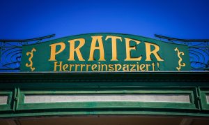 Eingang zum Wiener Prater mit dem Schild 'Prater – Herrrreinspaziert!' bei blauem Himmel