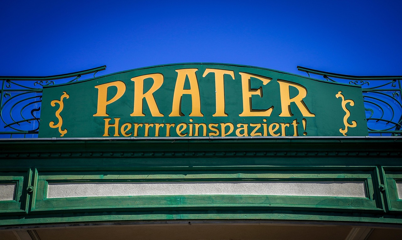 Eingang zum Wiener Prater mit dem Schild 'Prater – Herrrreinspaziert!' bei blauem Himmel