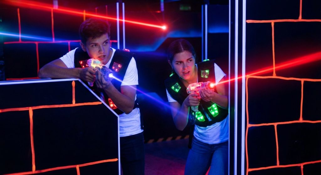 Zwei Jugendliche spielen Lasertag mit leuchtenden Westen und Infrarot-Markierern in einer neonbeleuchteten Arena.