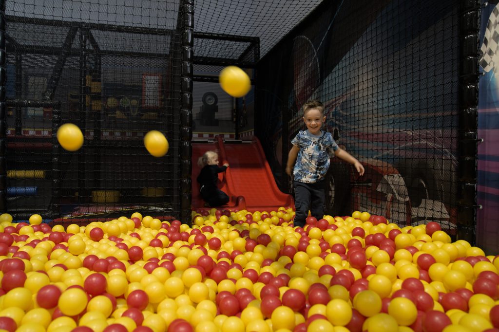 Kinder spielen in einem Bällebad mit roten und gelben Bällen in einer Indoor-Spielhalle
